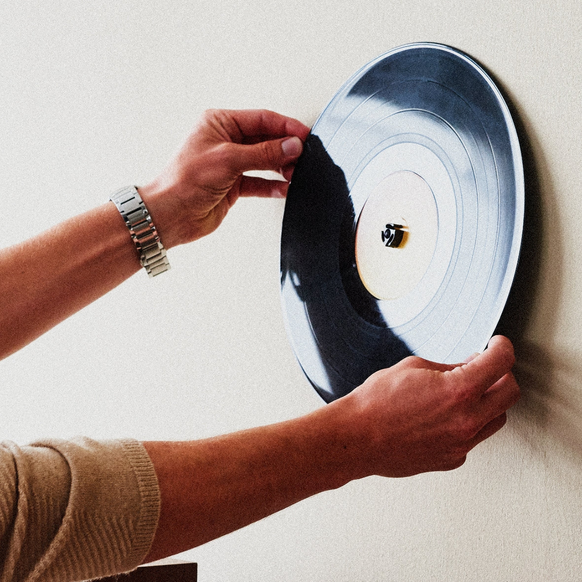 Hands holding a record up against the wall with the Twelve Inch Adapter