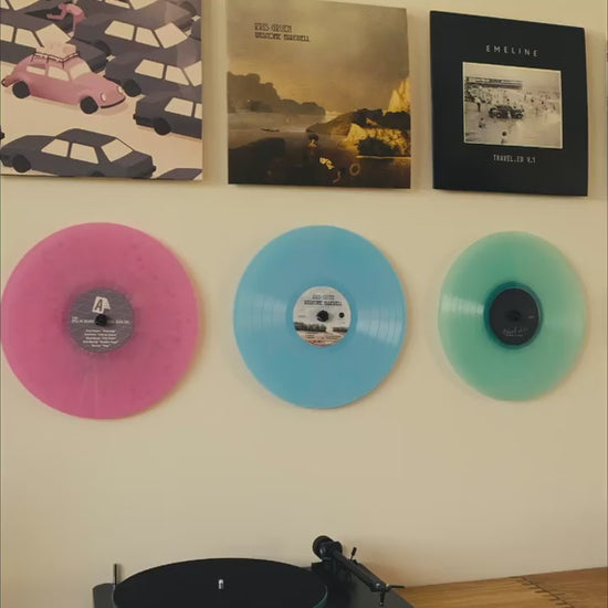 Showing both vinyl records and the albums on the wall, without frames og visible support